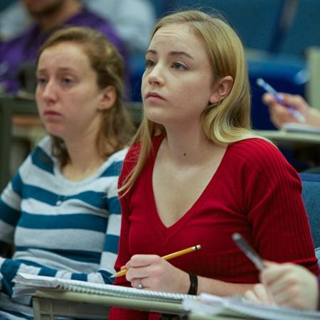 a student takes notes during a lecture